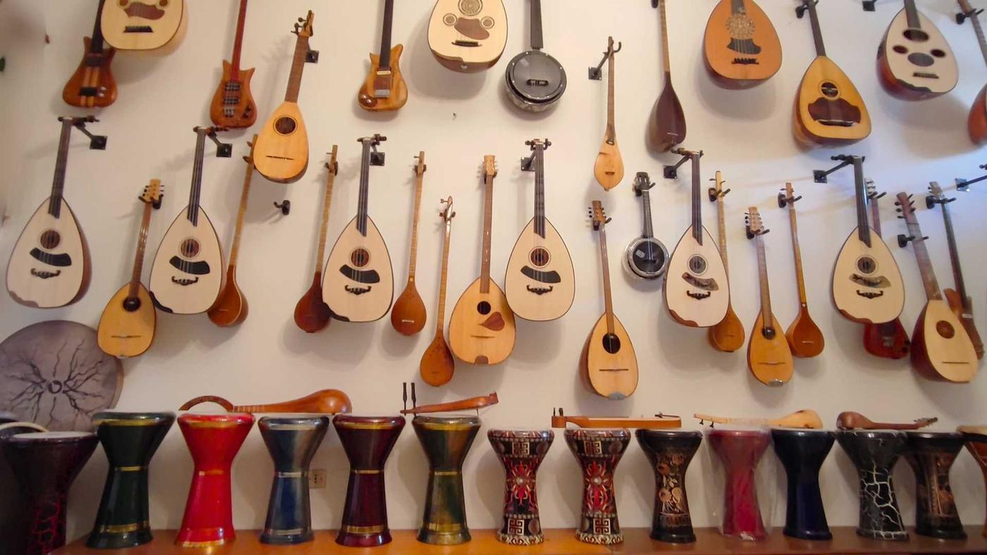A variety of string instruments and colorful drums displayed on a wall and table.